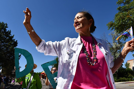Deb Haaland enthusiastically waves at a crowd of people.